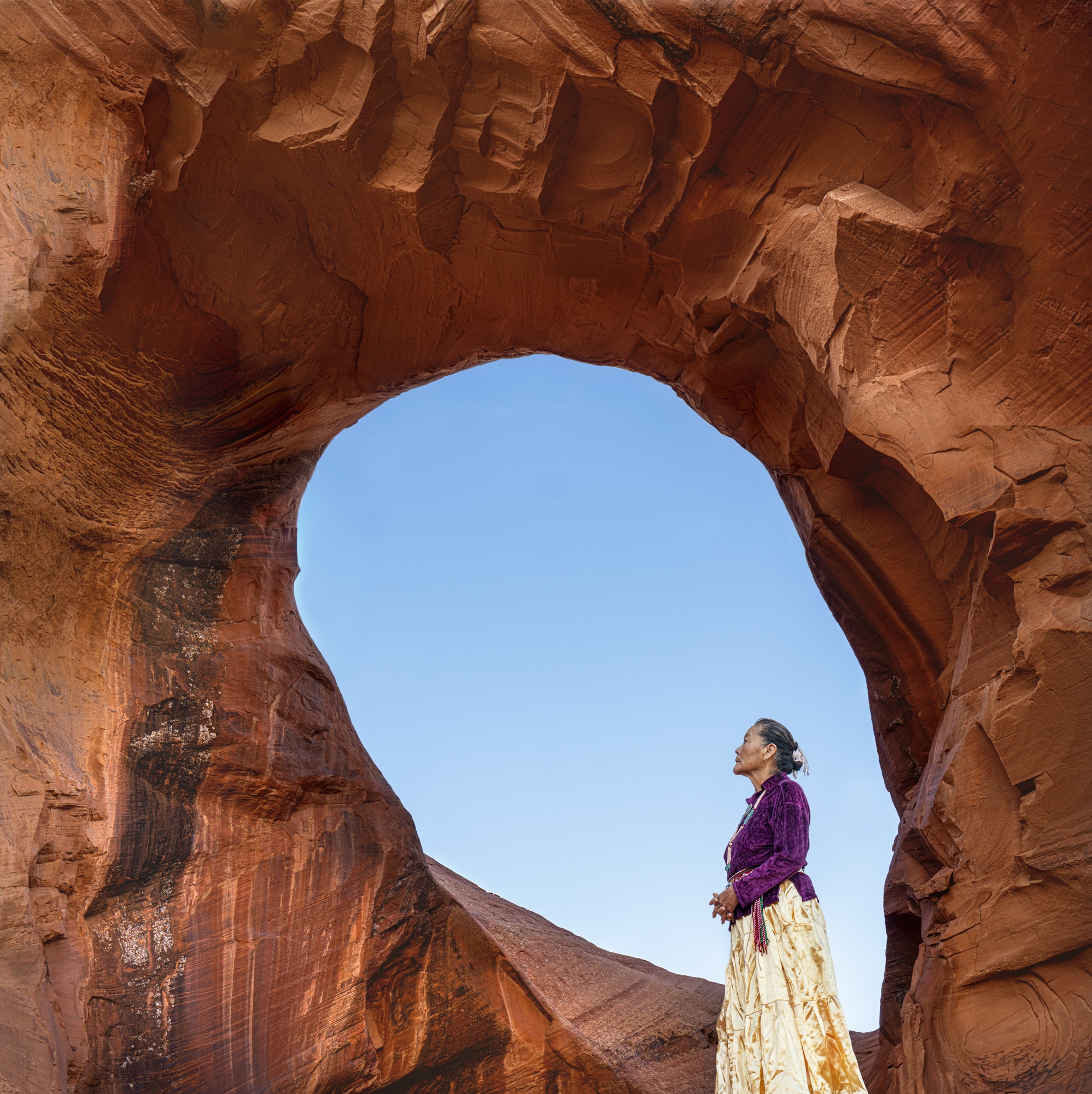 A Navajo woman from the Bitter Water clan stands before “The Ear of the Wind,” a portal to ancestral strength and survival.