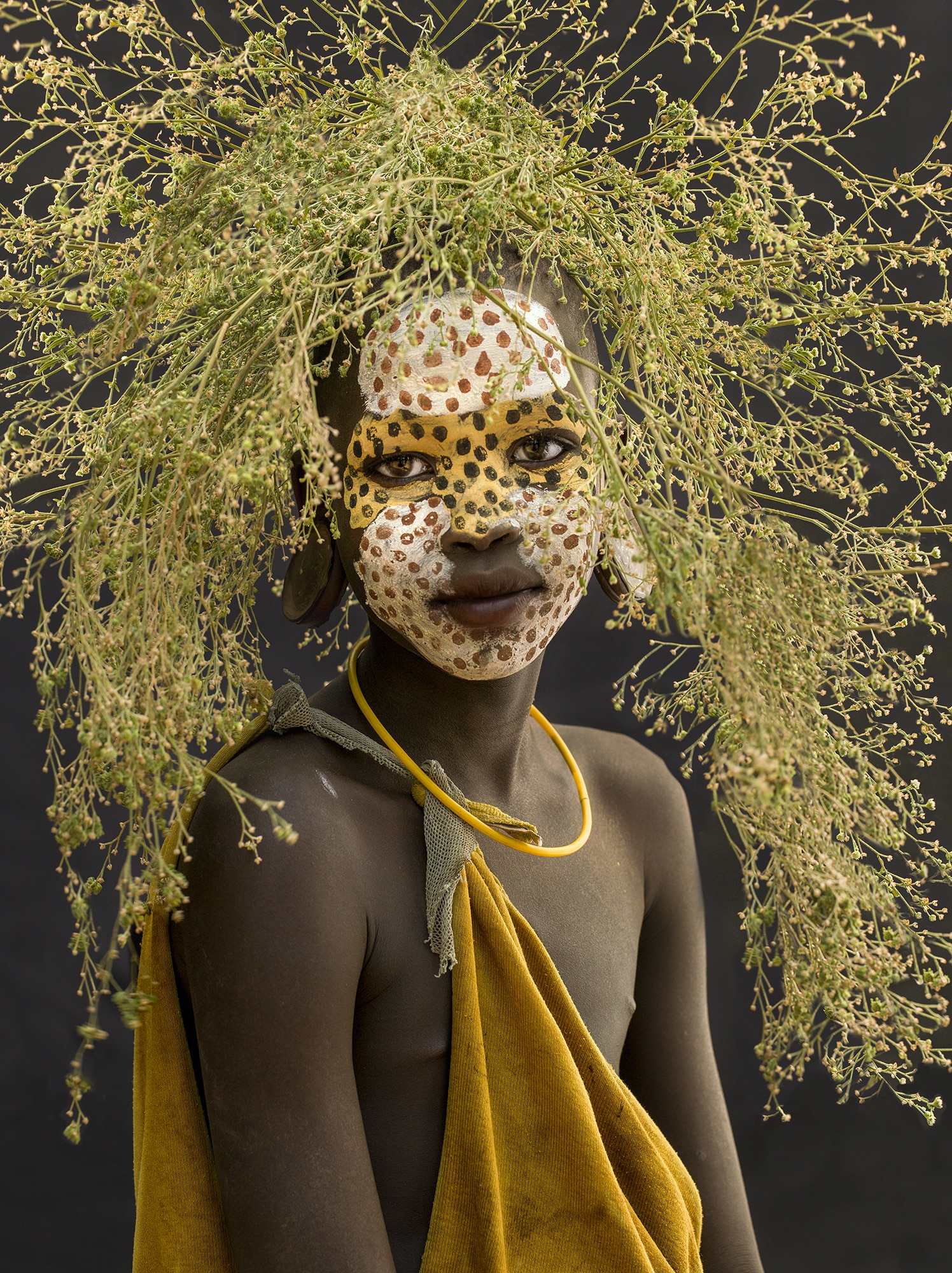 A Surma daughter adorned with natural elements, embodying the artistry and nomadic traditions of Ethiopia's Omo Valley.