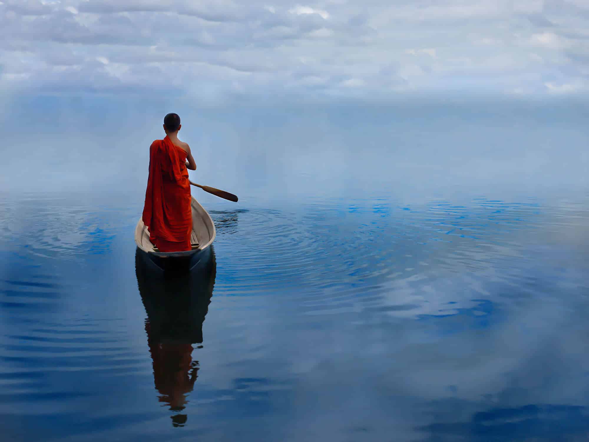 A serene Buddhist monk walks along the shores of Inle Lake in Myanmar, embodying peace and the timeless essence of eternity.